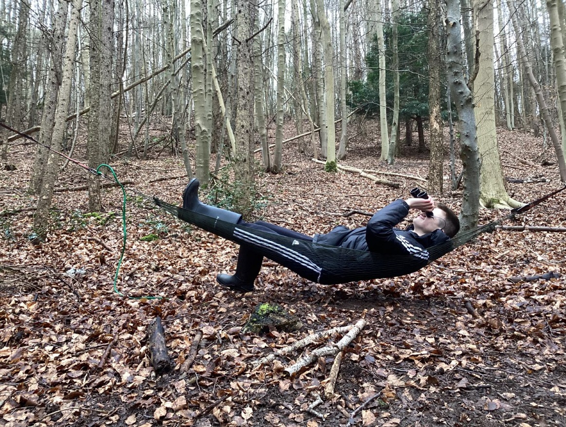 Pupil lying on hammock in the woodland