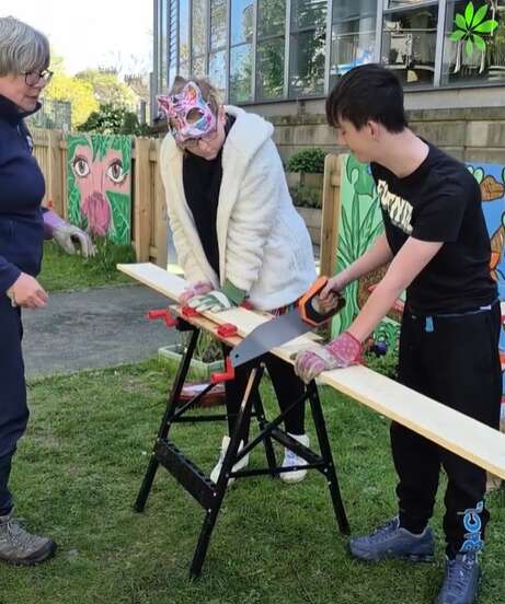 Young people sawing wood for a bug hotel in the Wild Thursdays Club at Sunderland Community Garde n.